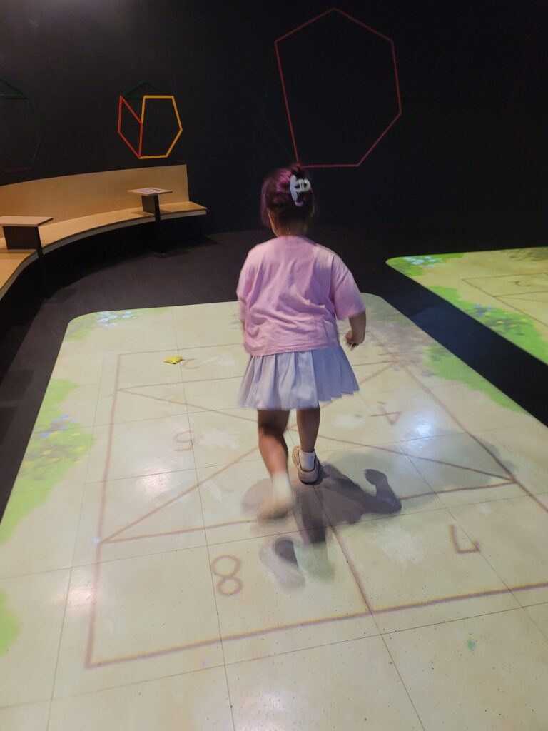 Child playing on an interactive projected light floor in a darkened room