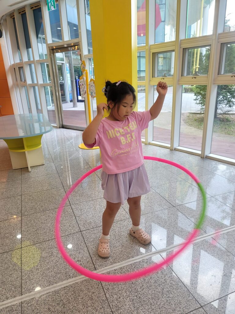 Child playing with a hula hoop in the bright glass lobby of Goyang Children's Museum