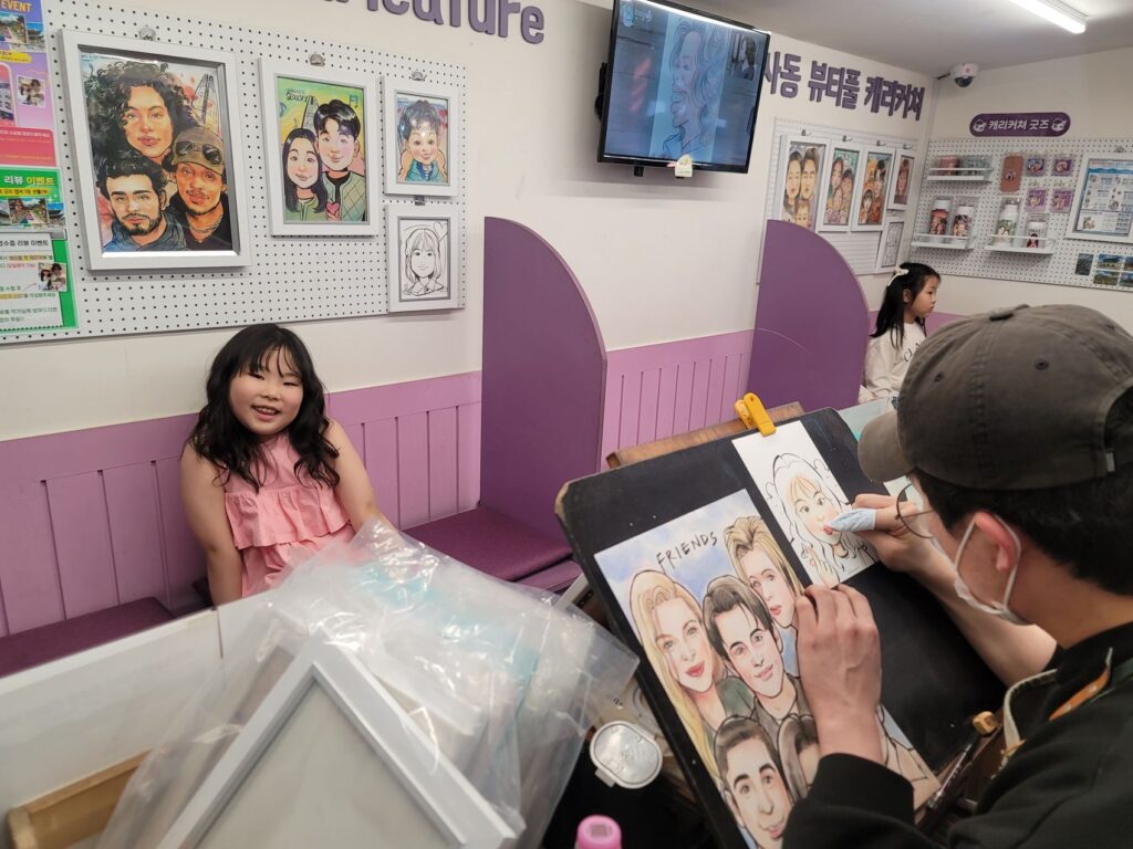 A caricature artist drawing a child's portrait in a small studio in Insadong, Seoul