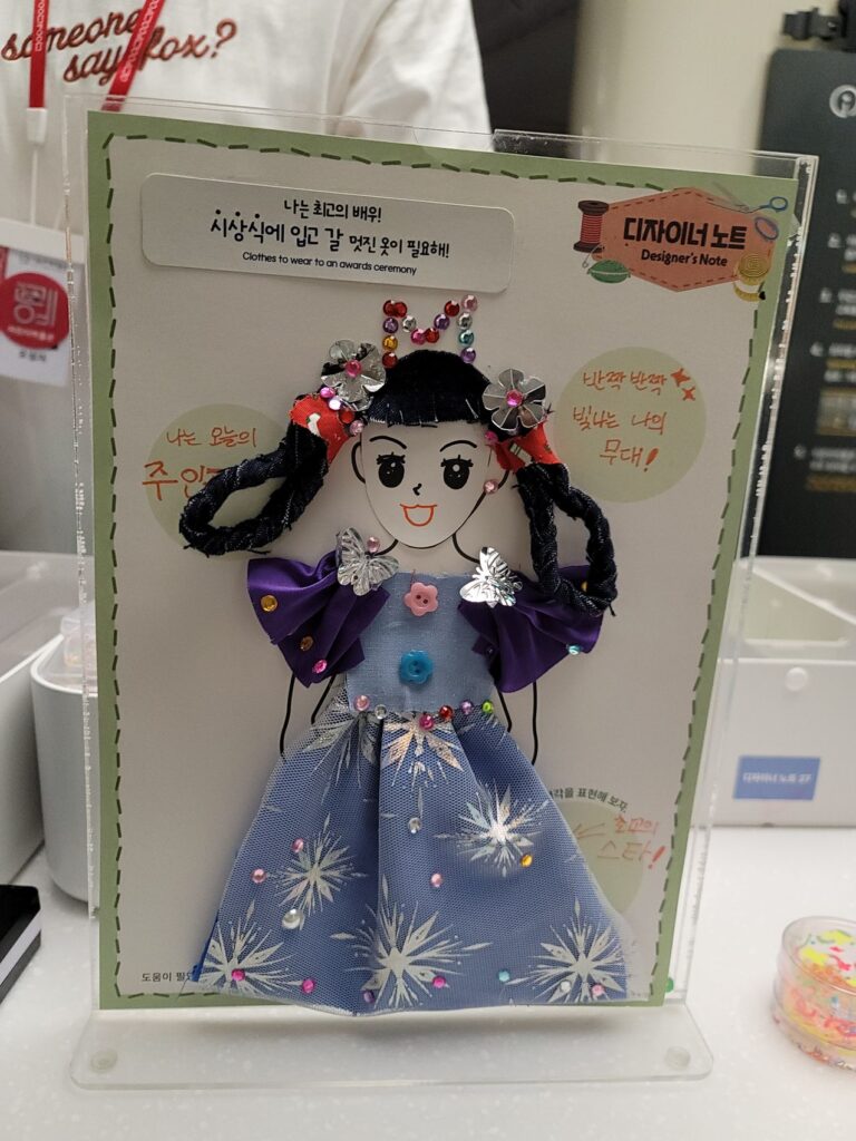 A paper doll dressed in fabric, sequins and buttons, made at the Seoul Museum of Craft Art Children's Museum