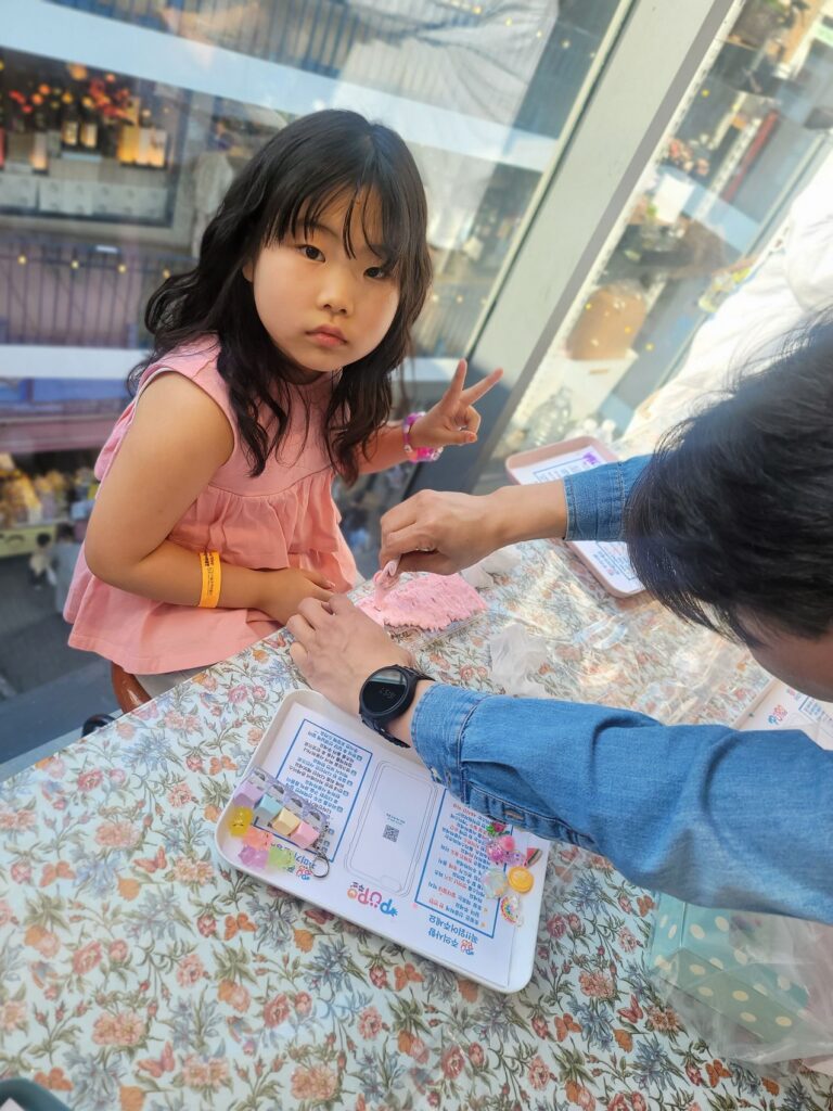 A child pressing clay into a keycap mould to make a keyring at a craft workshop in Insadong